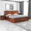 Wooden double bed with slatted headboard, matching footboard, and warm brown finish in a modern bedroom.